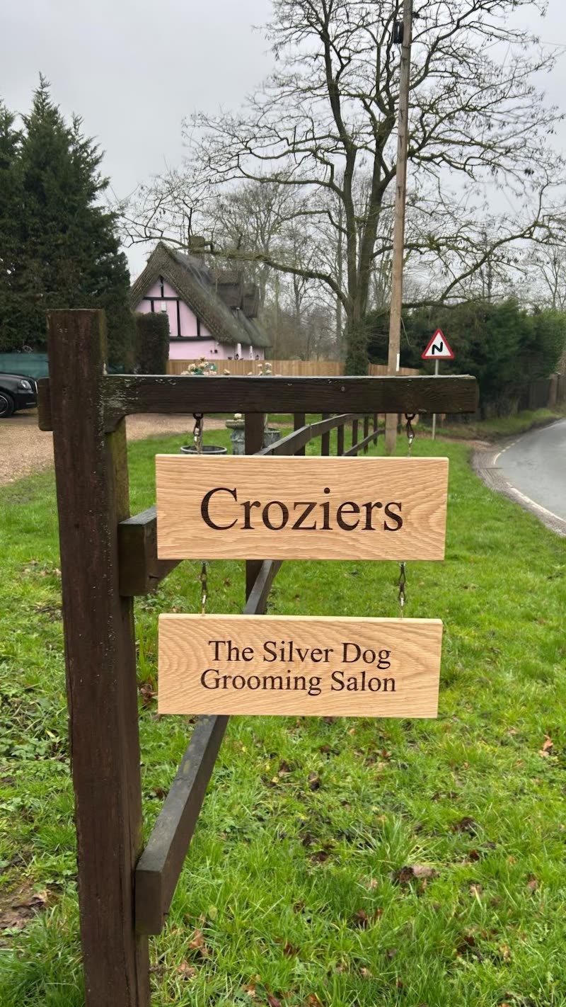 The roadside signpost on the grass verge at the entrance, with a country lane behind